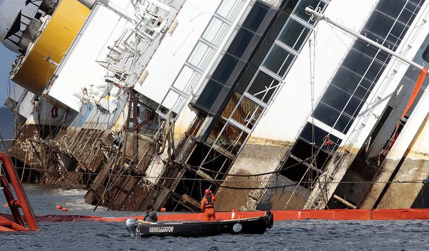Salvage crew workers are seen in front of the capsized Costa Concordia cruise liner after the start of the "parbuckling" operation outside Giglio harbour September 16, 2013. Engineering teams began lifting the wrecked liner upright on Monday, the start of