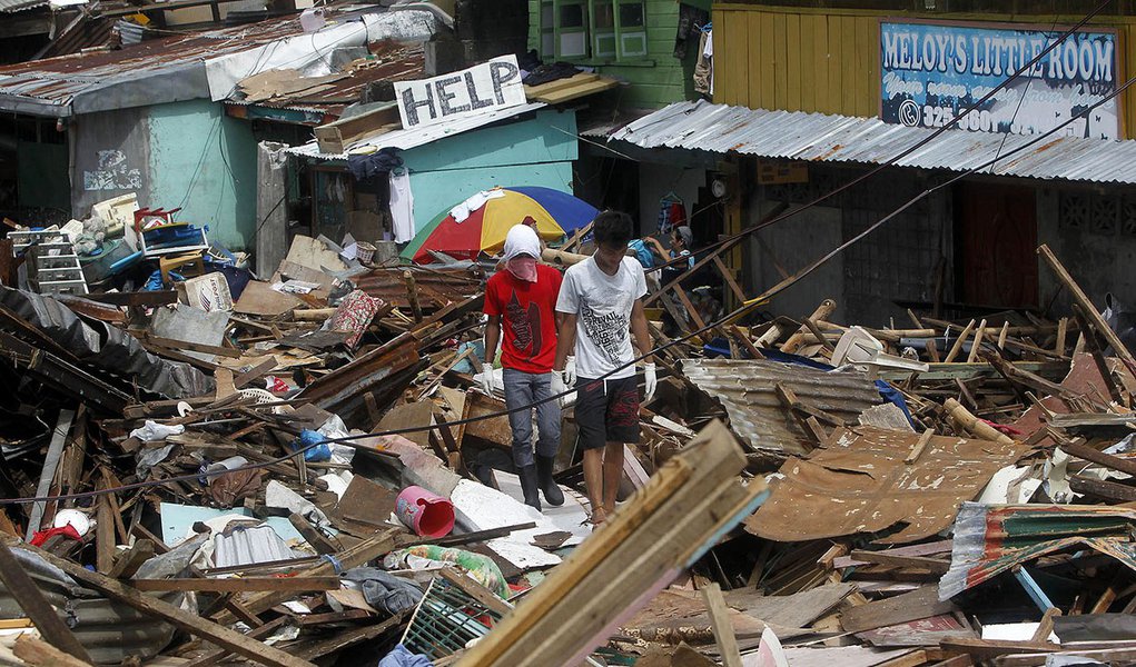 Residents walk past houses devastated by Typhoon Haiyan in Tacloban city, central Philippines November 13, 2013. Desperation gripped Philippine islands devastated by Typhoon Haiyan as looting turned deadly on Wednesday and survivors panicked over delays i