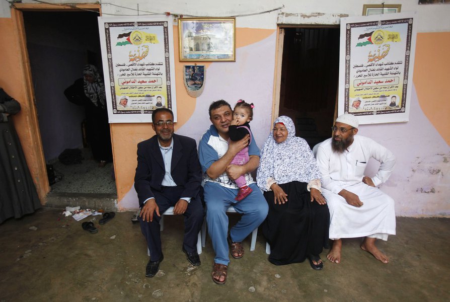 Freed Palestinian prisoner Ahmed al-Damoni (2nd L), who was held by Israel for 23 years, holds his niece as he sits next to his mother (2nd R) and relatives inside his family's house in the central Gaza Strip October 30, 2013. Israelis say al-Damoni was c