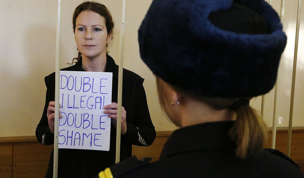 Greenpeace activist Ana Paula Alminhana Maciel from Brazil, one of the 30 people arrested over a Greenpeace protest at the Prirazlomnaya oil rig, holds a sign as she stands in a defendants' cage during a court session in St. Petersburg, November 18, 2013.