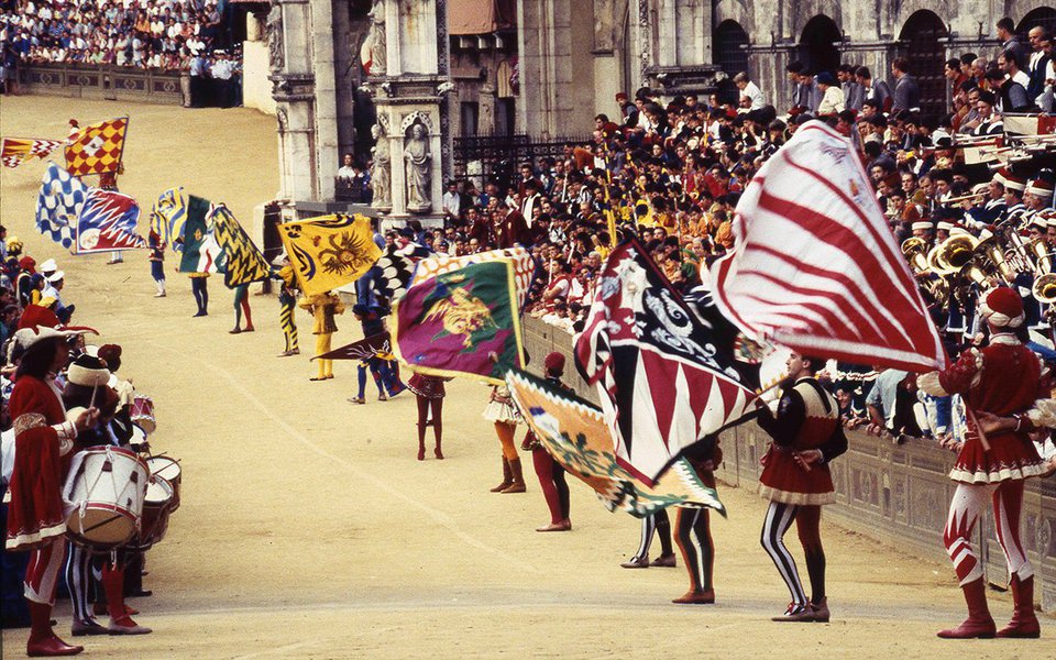 
Ritos e festas populares contam a mais colorida, vivaz e brilhante história da cultura e da psicologia dos povos. Isso é particularmente verdadeiro na Itália, cujo acervo de eventos tradicionais do gênero é um dos mais ricos do mundo. Não há dia do ano em que, em algum lugar da Península, a população não saia às ruas para comemorar sagras agrícolas, esportivas, religiosas, culturais. A maior parte dessas celebrações tem origem muito antiga, e muitas remontam inclusive aos tempos pré-cristãos. Na foto de abertura, o Pálio de Siena.
