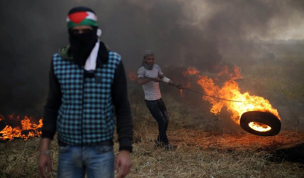 Manifestante palestino move pneu em chamas durante confronto com soldados israelenses na fronteira entre Israel e Gaza 05/04/2018 REUTERS/Ibraheem Abu Mustafa