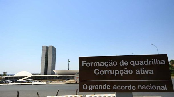 Início da semana na qual será votado o relatório do relatório do deputado Bonifácio de Andrada (PSDB-MG) pedindo o arquivamento da segunda denúncia, por obstrução da Justiça e organização criminosa - contra Michel Temer um adesivo foi colocado na placa que indica o acesso ao Congresso nacional com os dizeres "Formação de quadrilha, corrupção ativa – O grande acordo nacional"; padrão utilizado nas placas é o mesmo empregado pelo governo do Distrito Federal nas placas indicativas oficiais