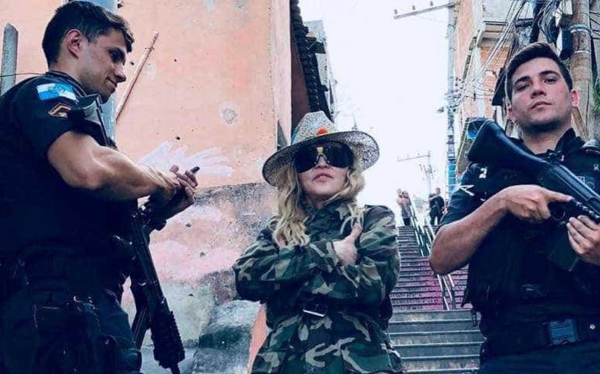 O policial Raiff Medeiros negou que a Polícia Militar do Rio de Janeiro tenha escoltado a cantora Madonna em visita ao Morro da Providência, conforme acusou o Movimento Brasil Livre (MBL) em postagem nas redes sociais; "Foi de surpresa", disse Raiff, que posou para foto com a artista norte americana; após a visita à comunidade na quarta-feira (25) Madonna publicou nas redes sociais uma foto ao lado de policiais armados com fuzis