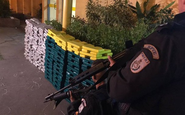 Policiais militares (PM) apreenderam quase uma tonelada de maconha, na zona oeste da cidade do Rio; policiais do Batalhão de Policiamento em Vias Especiais receberam a informação de que criminosos estavam reunidos em um posto de gasolina, na Estrada do Mendanha, próximo à Avenida Brasil; ao chegar ao local, os policiais encontraram um homem, que esperava outros dois comparsas para fazer a distribuição da droga