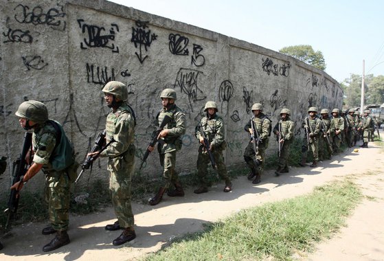 Um novo tiroteio foi ouvido na madrugada de hoje (23) na comunidade da Rocinha, na zona sul do Rio de Janeiro; de acordo com a Assessoria de Comunicação Social do Estado-Maior Conjunto das Operações em Apoio ao Plano Nacional de Segurança Pública, por volta das 4h30, elementos armados tentaram romper bloqueio do cerco estabelecido pelas Forças Armadas nas proximidades da Rua General Olímpio Mourão Filho; na operação, foram presos pela Polícia do Exército os cinco ocupantes de um veículo Renault Symbol e apreendidos um fuzil AK47 calibre 7,62mm com numeração raspada e quatro carregadores