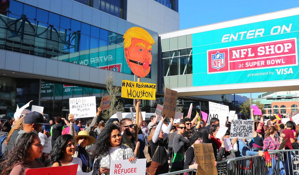 Em um jogo histórico decidido pela primeira vez na prorrogação, o New England Patriots venceu o Atlanta Falcons e ganhou seu quinto título do Super Bowl, o maior e mais lucrativo evento esportivo dos Estados Unidos que aconteceu neste domingo (6), em Houston; jogo, porém,  foi marcado por protestos contra o presidente norte-americano, Donald Trump; cerca de 500 pessoas caminharam até a arena onde aconteceu o evento esportivo, em uma marcha com cartazes e gritos de ordem contra o mandatário republicano