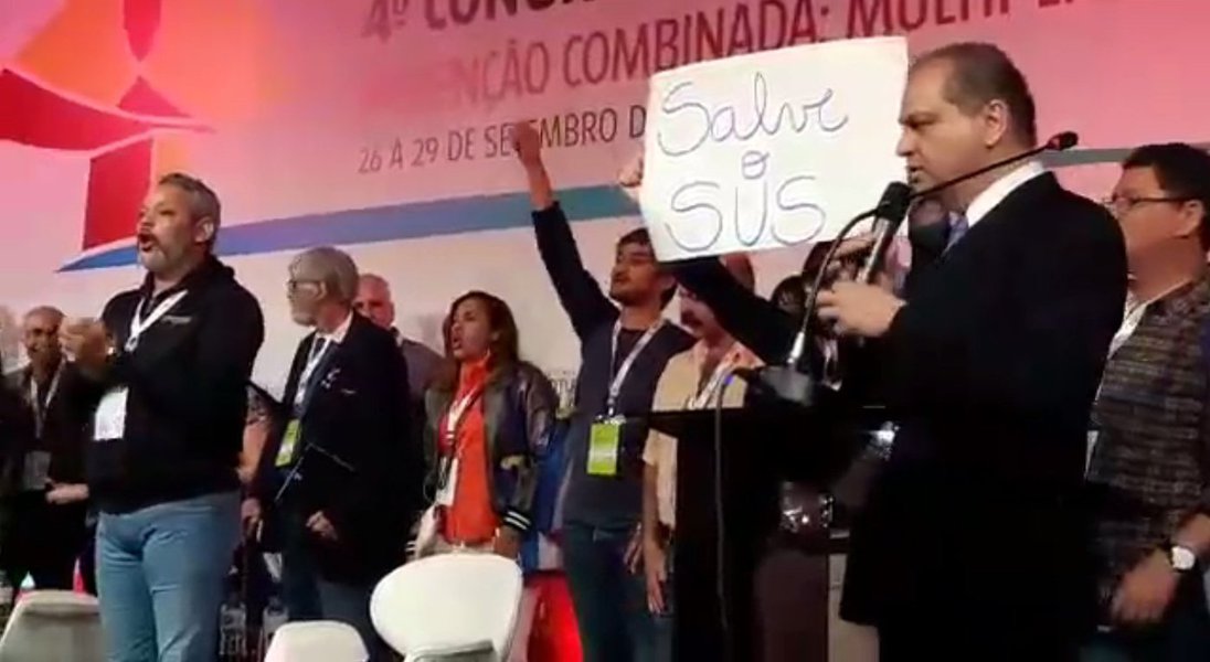 O ministro da Saúde, Ricardo Barros, teve o discurso interrompido por manifestantes nesta sexta-feira (29) durante o 11º Congresso de HIV/Aids e 4º Congresso de Hepatites Virais (HepAids 2017), que acontece em Curitiba; portando cartazes com dizeres “Salve o SUS”, “Nenhum Direito a Menos”, os manifestantes gritavam “Fora Temer” e o “SUS é nosso, ninguém tira da gente!”