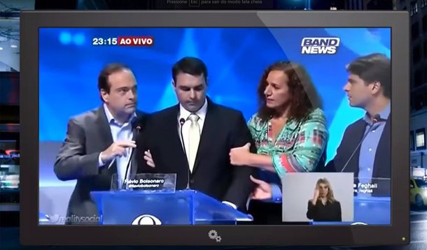 O candidato à Prefeitura do Rio Flávio Bolsonaro (PSC) passou mal ontem durante o debate realizado pela Bandeirantes, que precisou ser interrompido; médica, a deputada Jandira Feghali (PCdoB), que também está na disputa, tentou ajudar; Flávio e o pai, o deputado federal Jair Bolsonaro (PSC), reagiram: "Sai daqui"; ela contou o episódio que aconteceu nos bastidores logo após o reinício do debate, para o qual Flávio Bolsonaro não voltou; em 2014, Flávio Bolsonaro debochou quando Dilma passou mal em debate