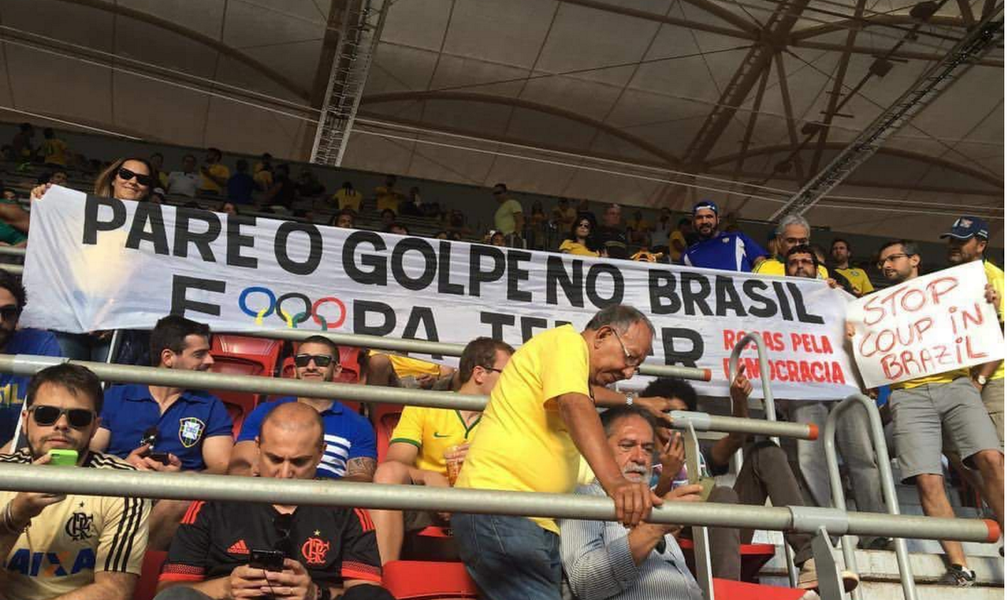 No jogo entre a seleção olímpica brasileira e África do Sul no estádio Mané Garrincha (Brasília), nesta quinta-feira (4), um grupo de torcedores, no entanto, furou o bloqueio da segurança e, com faixas, denunciou o golpe aos torcedores de outros países; Globo, no entanto, não mostrou as cenas