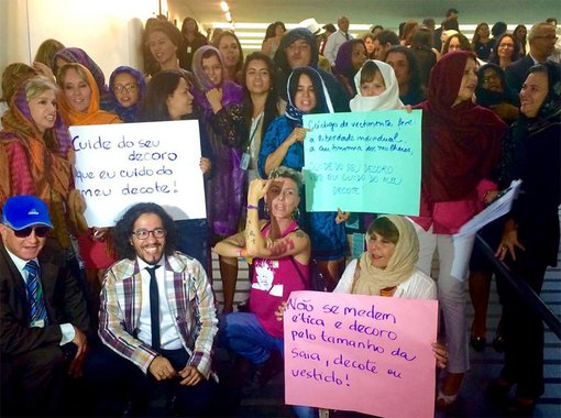 "Cuide do seu decoro que eu cuido do meu decote", dizia um cartaz; "Não se medem ética e decoro pelo tamanho da saia, decote ou vestido", destacava outro; a hashtag MaisÉTICAMenosESTÉTICA ganhou as redes sociais; movimento é contra o projeto da deputada Cristiane Brasil (PTB-RJ), que proíbe decote e minissaias para mulheres e determina ternos pretos, azuis e cinzas para homens; "Ação é mais uma tentativa de se dedicar ao que não importa", criticou Jean Wyllys (PSOL-RJ)