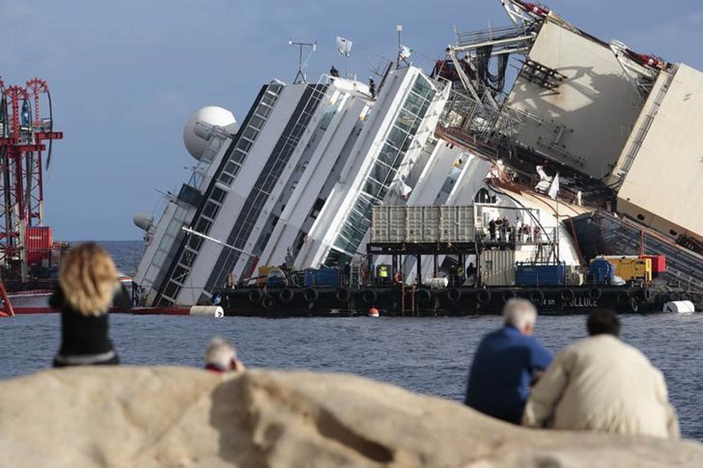 Pessoas olham navio de cruzeiro Costa Concordia tombado na costa da Toscana, na ItÃ¡lia. 16/09/2014 REUTERS/Tony Gentile