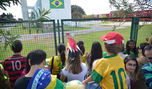 O hotel em que a seleção brasileira está hospedada em Brasília, de frente para o Lago Paranoá, virou ponto turístico; o Brasil enfrenta a seleção de Camarões no Estádio Nacional Mané Garrincha, pela última rodada do Grupo A, da primeira fase da Copa do Mundo; na grade do hotel, torcedores estão concentrados, quando que a equipe chegou à capital federal