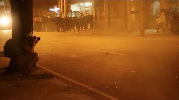 Com uma câmera na mão e uma máscara de gás na cara