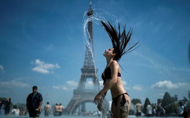 Mulher se banha em frente à Torre Eiffel em dia de calor forte