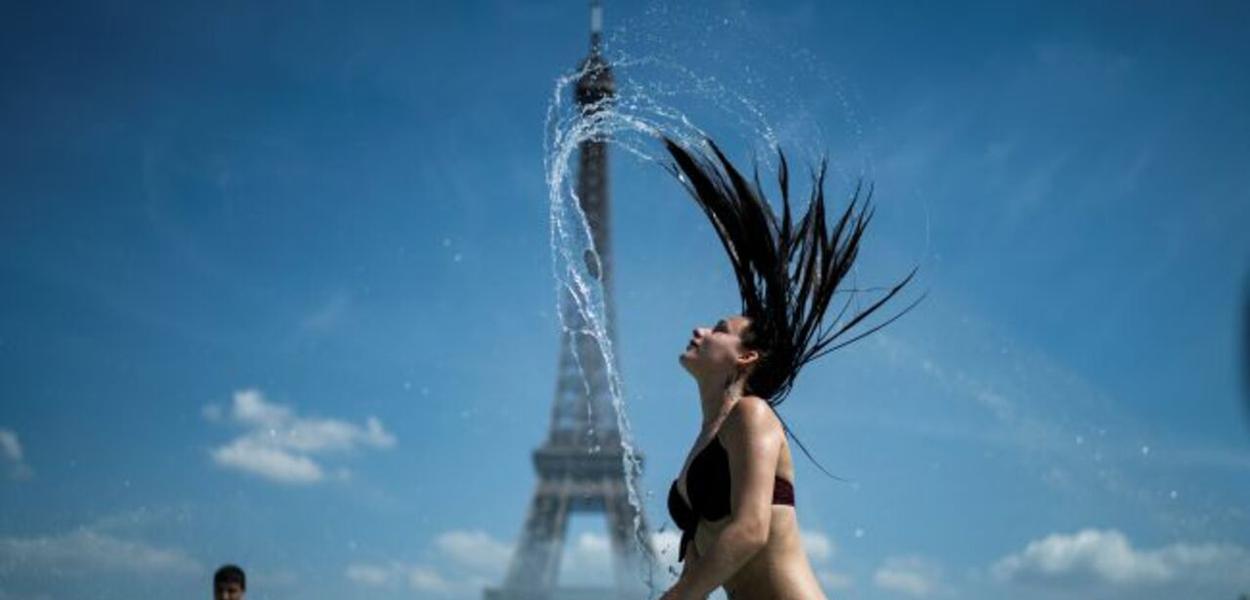 Mulher se banha em frente à Torre Eiffel em dia de calor forte