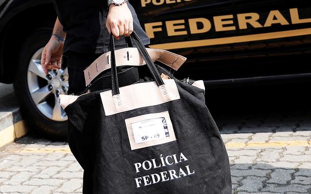 Policial federal carrega uma bolsa ao chegar à sede da Polícia Federal em São Paulo