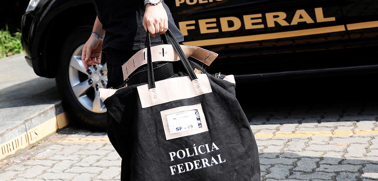 Policial federal carrega uma bolsa ao chegar à sede da Polícia Federal em São Paulo