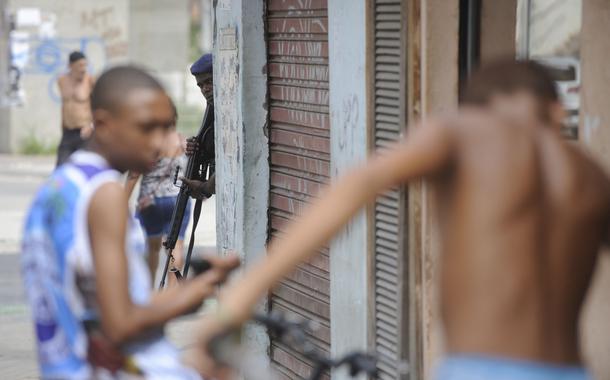Policial armado observa jovens negros na favela