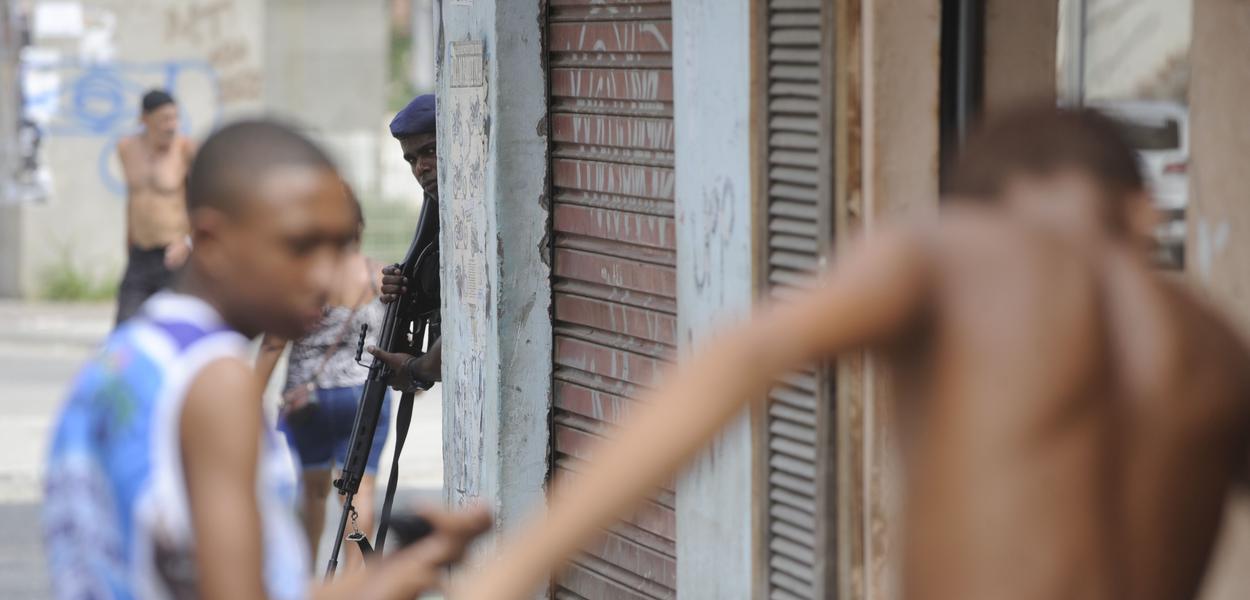 Policial armado observa jovens negros na favela