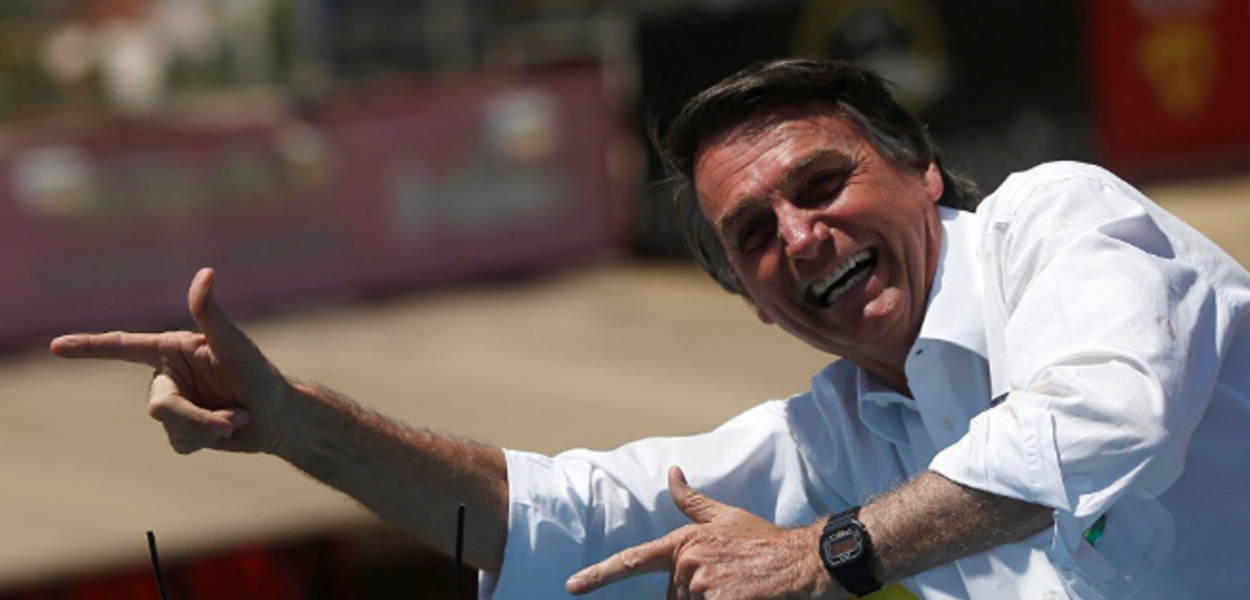 Jair Bolsonaro faz sinal de armas com as mãos