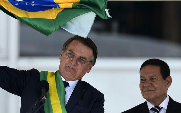 Presidente Jair Bolsonaro e o vice-presidente Hamilton MourÃ£o exibem uma bandeira nacional durante discurso no parlatÃ³rio do PalÃ¡cio do Planalto.