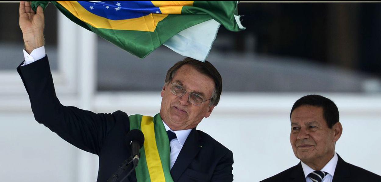 Presidente Jair Bolsonaro e o vice-presidente Hamilton MourÃ£o exibem uma bandeira nacional durante discurso no parlatÃ³rio do PalÃ¡cio do Planalto.