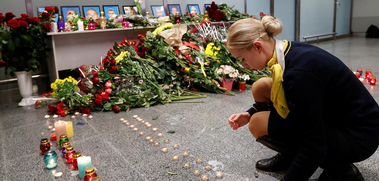 Colega de tripulantes do voo da Ukraine International Airlines que caiu pouco após decolar de Teerã coloca velas em memorial no aeroporto Boryspil, em Kiev
