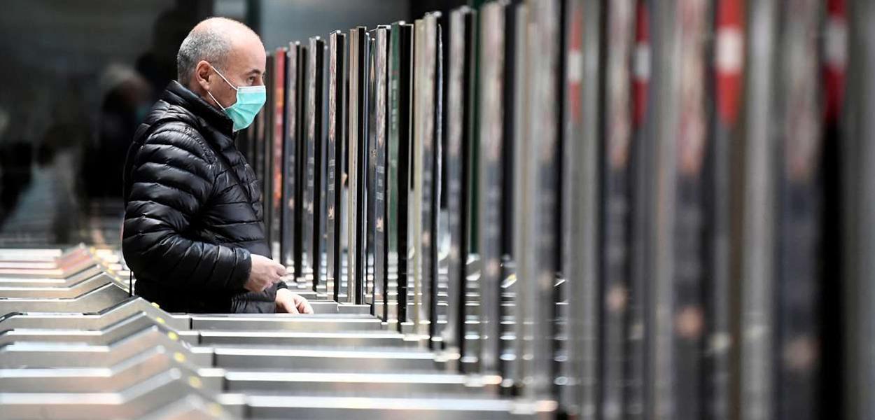 Homem de máscara em estação de metrô de Milão