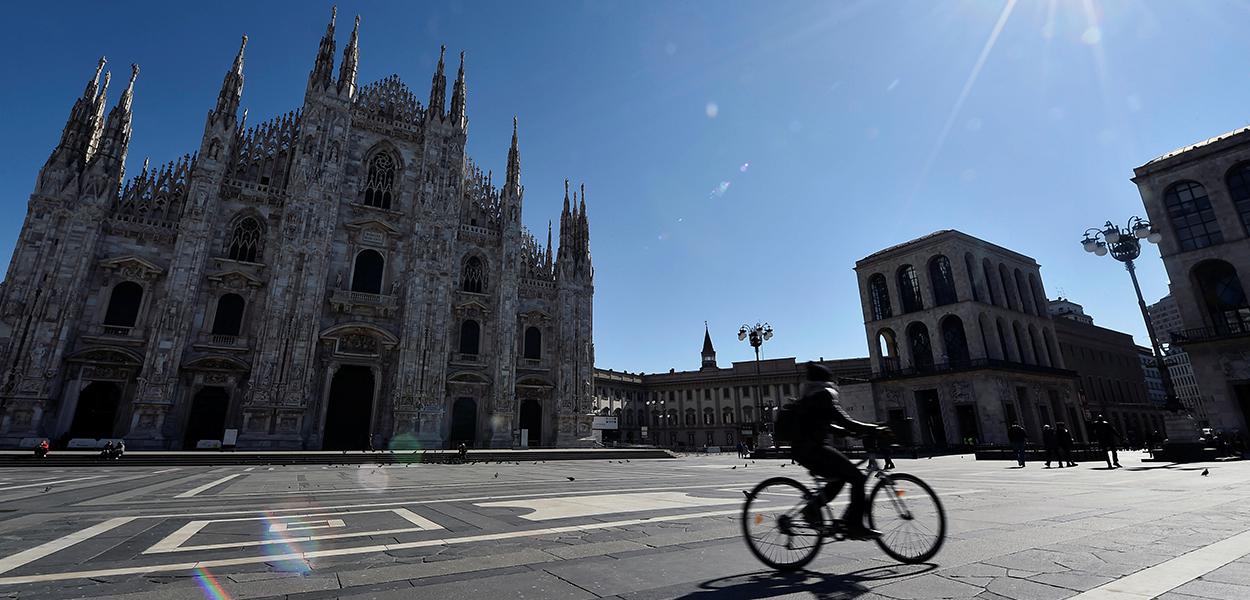 Ciclista passa em frente à catedral de Milão, com ambientes públicos desertos por conta do coronavírus