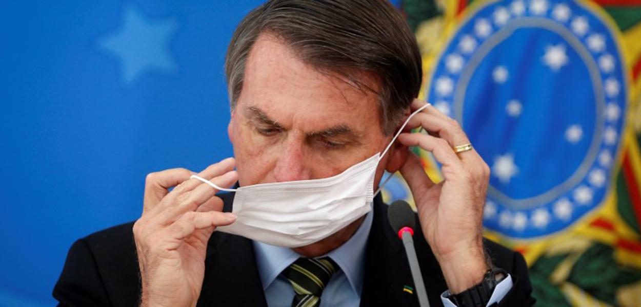 Presidente Jair Bolsonaro ajusta máscara de proteção durante coletiva sobre medidas para evitar a disseminação do coronavírus