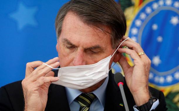 Presidente Jair Bolsonaro ajusta máscara de proteção durante coletiva sobre medidas para evitar a disseminação do coronavírus