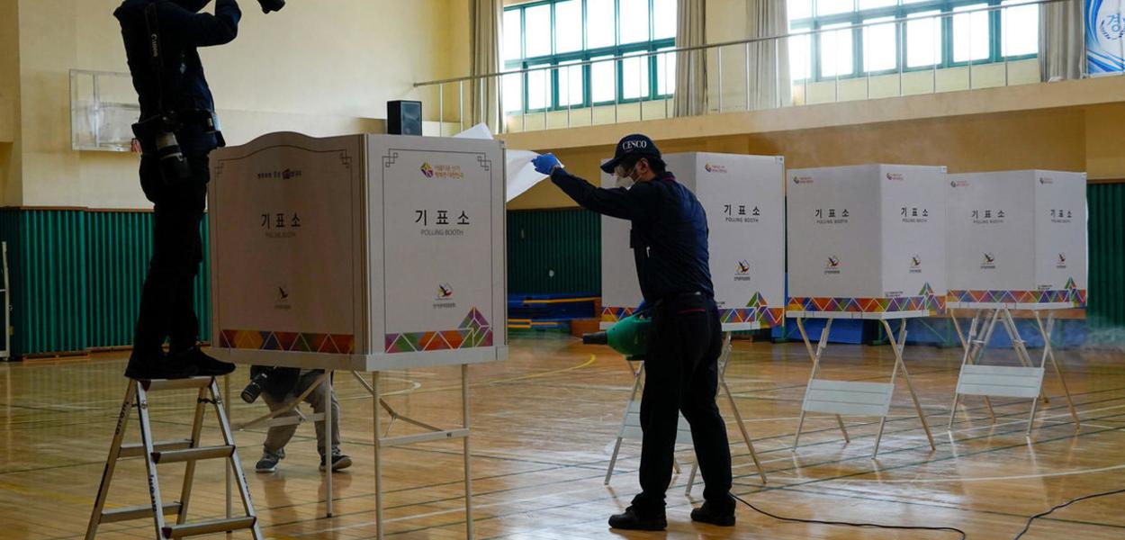 Funcionários de uma empresa de limpeza preparam uma sala que vai servir de seção eleitoral durante as eleições legislativas na Coreia do Sul, na quarta-feira, 15 de abril de 2020