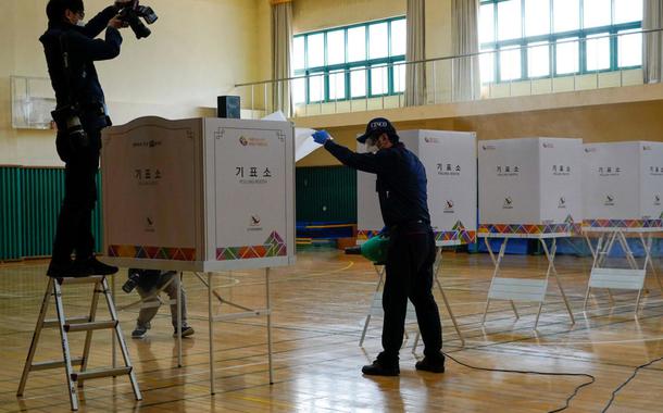 Funcionários de uma empresa de limpeza preparam uma sala que vai servir de seção eleitoral durante as eleições legislativas na Coreia do Sul, na quarta-feira, 15 de abril de 2020