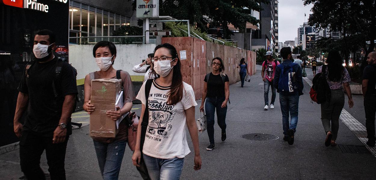 Protegidos com mascaras por causa da pandemia do Coronavírus, paulistanos caminham na avenida Paulista