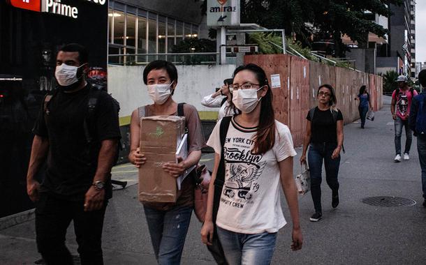 Protegidos com mascaras por causa da pandemia do Coronavírus, paulistanos caminham na avenida Paulista