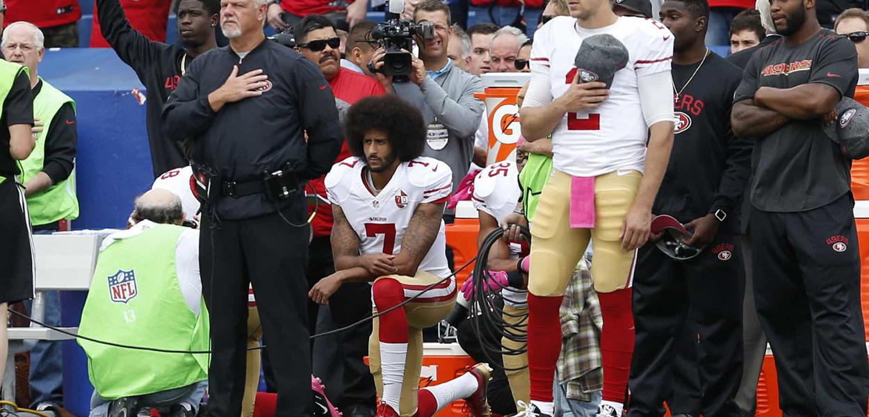 Colin Kaepernick ajoelhado durante hino dos EUA, contra o racismo