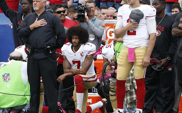 Colin Kaepernick ajoelhado durante hino dos EUA, contra o racismo