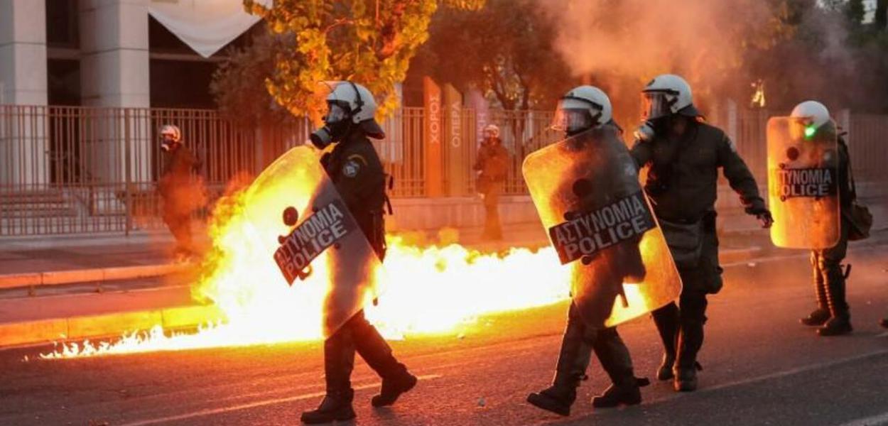 A polícia de choque passou por chamas enquanto reprimia manifestantes durante uma manifestação contra a morte na custódia policial de George Floyd, em Minneapolis, fora da embaixada dos EUA em Atenas, Grécia (3.6.20)