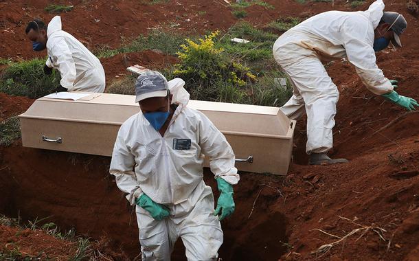 Coveiros com trajes de proteção enterram pessoa que morreu infectatada pelo novo coronavírus