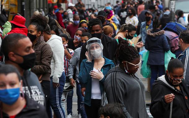 Pessoas com máscaras de proteção facial caminham em rua de comércio popular em São Paulo