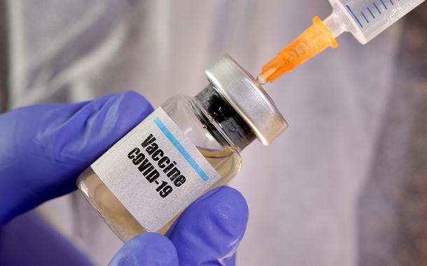 Pessoa manipula frasco com etiqueta nomeando vacina contra Covid-19.