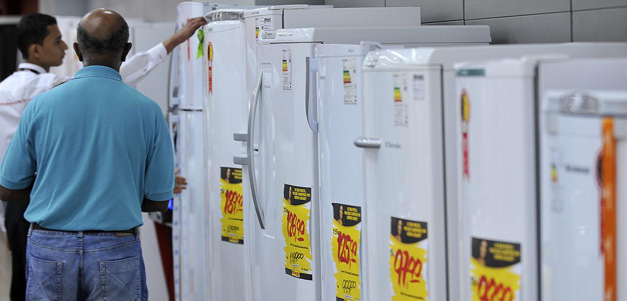 Vendedor mostra a cliente geladeiras da linha branca
