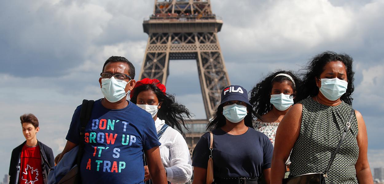 Pessoas com máscaras de proteção perto da Torre Eiffel, em Paris