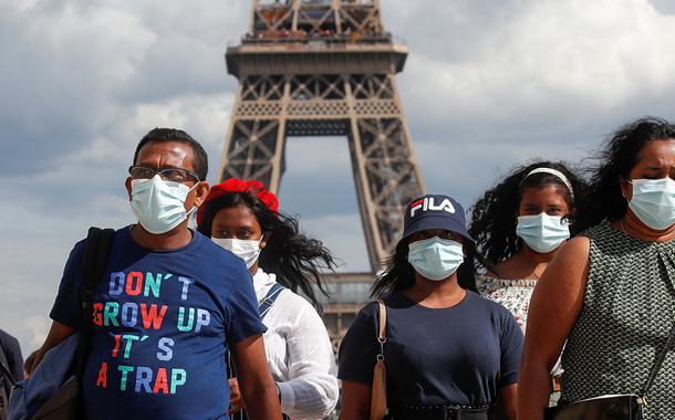 Pessoas com máscaras de proteção perto da Torre Eiffel, em Paris