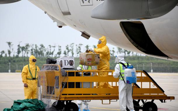 Trabalhadores em trajes de proteção desinfetam bagagens que chegam no Aeroporto Internacional de Wuhan