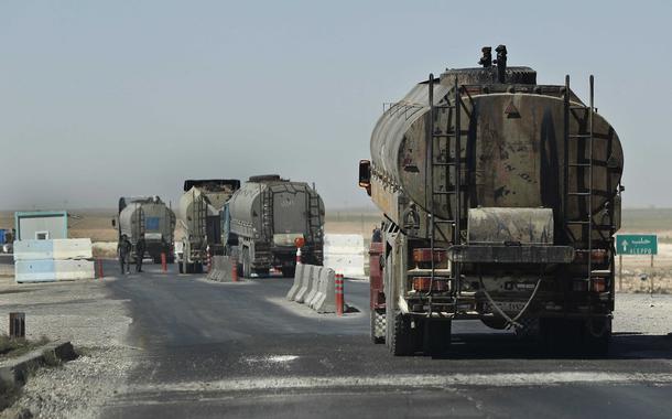 This April 4, 2018 photo shows a convoy of oil trucks passinf a Kurdish police (Assayesh) checkpoint, as they moving fuel produced in Kurdish-held areas in the east to other areas controlled by the same U.S-backed group to the west, on a highway in Hassakeh province, Syria. Since the Syrian government left the predominantly Kurdish area in northern Syria, the Syrian Kurds have been in control of some of the country's largest oil fields in Hassakeh province in the northeast starting in 2013. Many former government employees stayed on, and their salaries continued. (AP Photo/Hussein Malla)