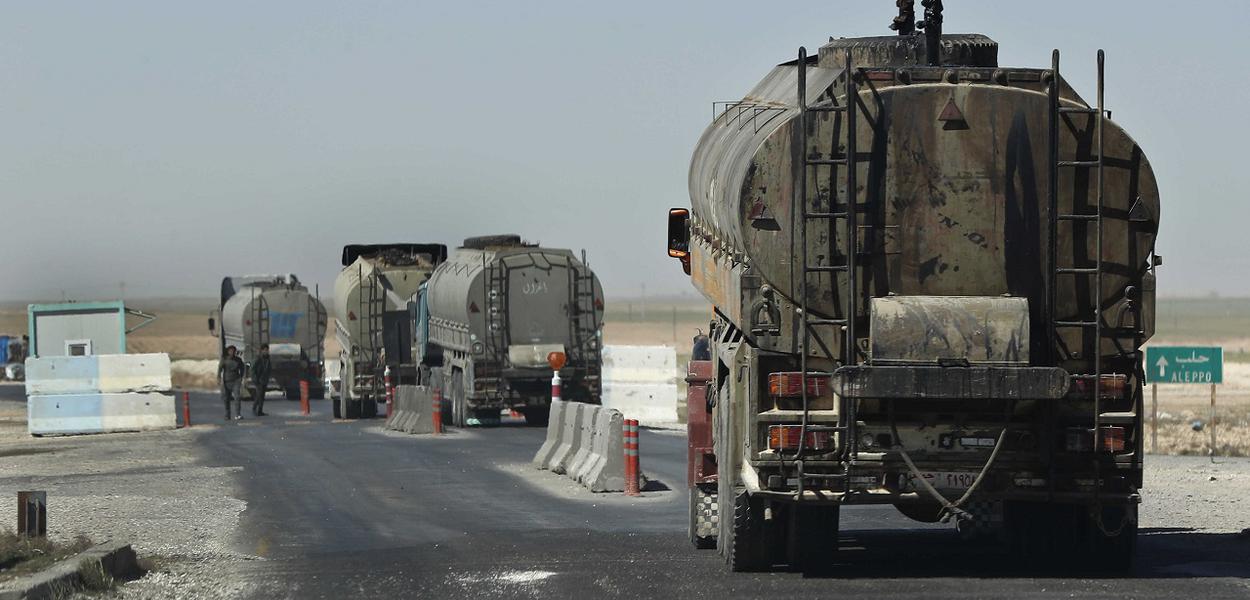 This April 4, 2018 photo shows a convoy of oil trucks passinf a Kurdish police (Assayesh) checkpoint, as they moving fuel produced in Kurdish-held areas in the east to other areas controlled by the same U.S-backed group to the west, on a highway in Hassakeh province, Syria. Since the Syrian government left the predominantly Kurdish area in northern Syria, the Syrian Kurds have been in control of some of the country's largest oil fields in Hassakeh province in the northeast starting in 2013. Many former government employees stayed on, and their salaries continued. (AP Photo/Hussein Malla)