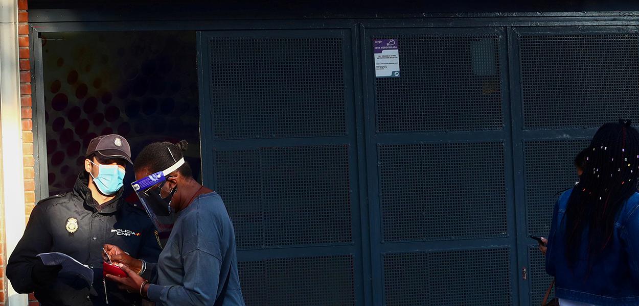 Agente da polícia nacional da Espanha checa documentos de mulher em Madri