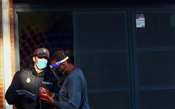 Agente da polícia nacional da Espanha checa documentos de mulher em Madri